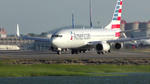 American Airlines jet plane turns to runway, Boston harbor waters edge, Logan Airport Boston Massachusetts USA, July 5, 2018