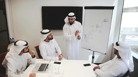 Four businessmen in dubai working in their office, planning the future development of the company