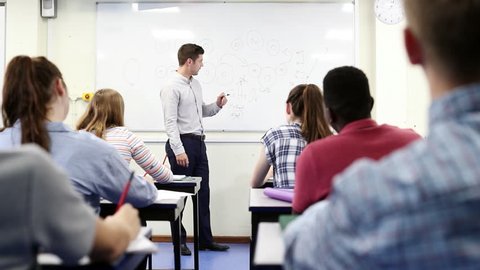 Male High School Tutor At Whiteboard Teaching Science Class