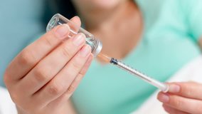 Closeup 4k video of young woman filling syringe with medicines from ampule