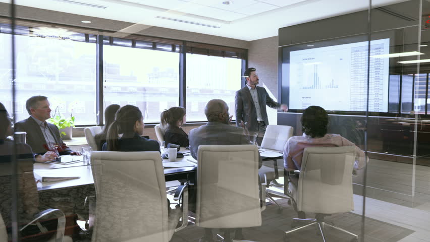 Dolly shot of business people in meeting at board room seen through glass Royalty-Free Stock Footage #1016241475
