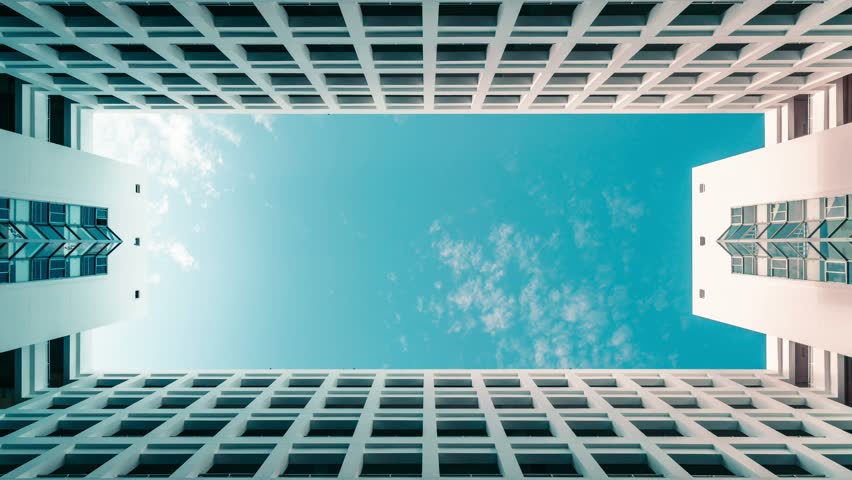 Timelapse of modern symmetrical architecture building with blue cloudy sky, abstract low angle clouds skyscaper shot Royalty-Free Stock Footage #1016241691