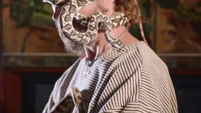 Snake on the man's face. Portrait of mad bearded hipster with snakes cawling on his head and face. Terrible video with snakes in role of domestic pets
