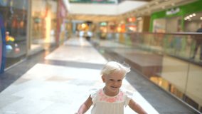 Shopping day of a modern family. The little smilling girl with packages walks with the family on big shopping center. Child run with packages on the Mall. happy child . shopping girl bag. slow-motion