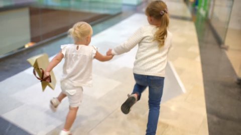 Shopping day of a happy family. little girls with packages walks with family on big shopping mall center. children running with bags on mall. shopping girl bag. happy family shopping child slow-motion