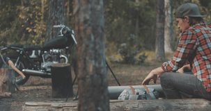 Hiker friends sitting around camp fire. Outdoor camping picnic in forest. Freedom lifestyle scene. Young couple in love sit by fireplace and talk. 4K video shooting by handheld gimbal
