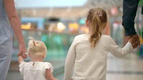 Happy family of four doing shopping. Family in mall. Children at mall with parents. Family shopping in big store. Family walking through shopping mall carrying sale bags. shopping girl bag slow-motion