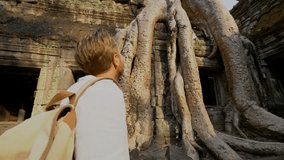 Young man traveling in Cambodia visiting the temples of Angkor wat complex. People travel discovery Asia concept. Shot at sunset, one man only, adventure exploration in Siem Reap, Southeast Asia.4K