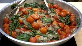Salad of red ripe tomato and other ingredients in a bowl with tongs. HD video
