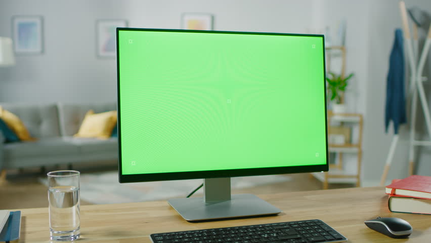 Modern Personal Computer with Green Mock-up Screen Display Standing on the Desk in the Cozy Living Room. A Man with Mobile Phone Walks Through His Flat. Shot on RED EPIC-W 8K Helium Cinema Camera. | Shutterstock HD Video #1016261905