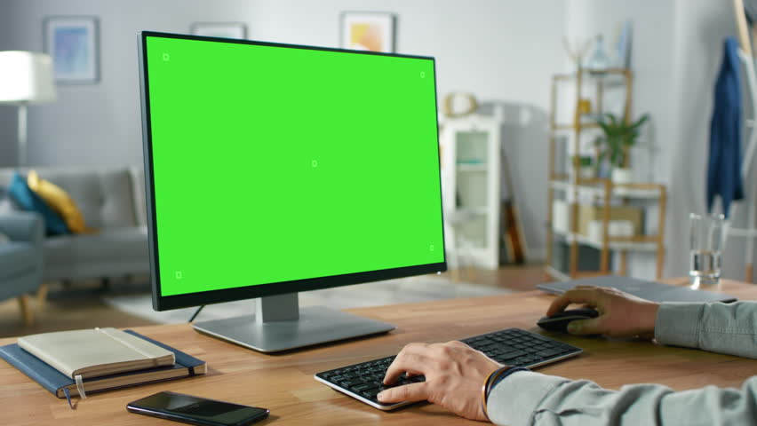 Over the Shoulder Shot of Professional Freelancer Working on Green Mockup Screen Personal Computer From Home. Man's Hands Typing, He's Browsing Through the Internet, Using Computer In Living Room. | Shutterstock HD Video #1016261986