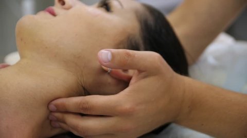 Woman doing neck massage at the reception of the chiropractor. Men's hands do massage of the cervical spine to an attractive girl. Massaging pain points