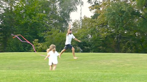 Happy family together in the park. Having fun and playing with kite. Slowmotion.