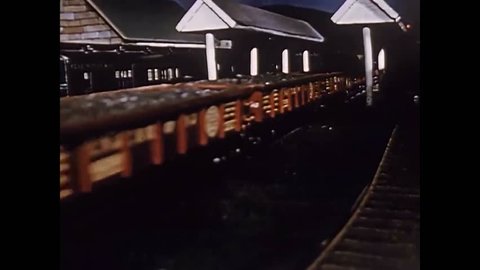 CIRCA 1950s - A clocktower is shown at a train station as well as trains in transit in a scale model of a rail transport system in a town.
