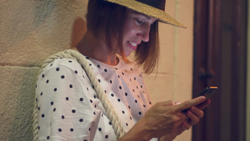 Attractive young woman texting outdoors at night