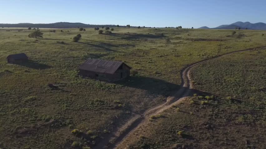 Aerial orbit of an old log cabin on a large prairie