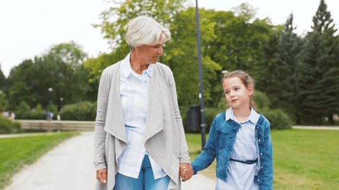 family, leisure and people concept - happy grandmother and granddaughter walking at summer park Video stock