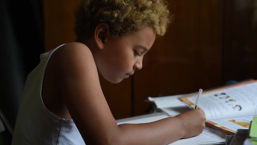 Schoolboy doing homework in his room in the home. Cute african american boy sitting  at the table and thinking and writing in his notes. Home education for kids.  Boy learning something from his book. Royalty-Free Stock Footage #1016284633