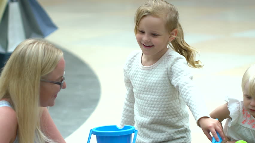 Shopping day of a modern family. child play in mall. Cute blond babe is playing with toys in the mall. Children