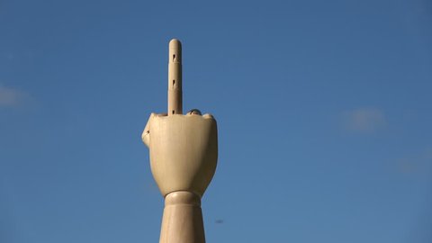 Wooden hand finger symbols  concept middle finger sign in  gesture meaning fuck you or fuck off rotating on blue sky background