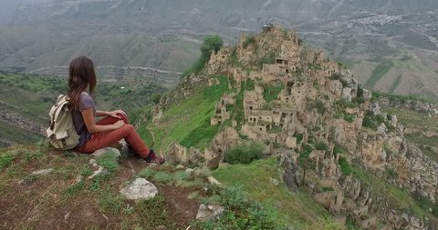Woman Sitting on Rock and Looking at the Old Abandoned Mountain Village - Gamsutl. Dagestan, Russia

