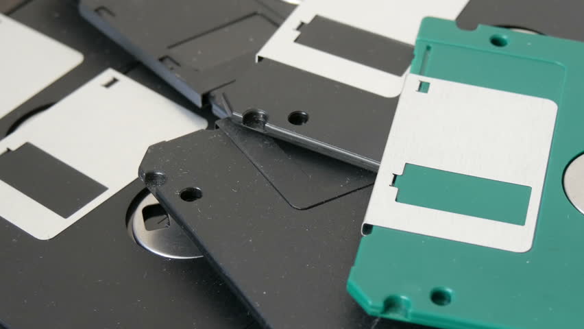 Close up top view of many 3.5 inch computer floppy disks or diskette scattered on a flat surface vintage technology. Woman