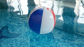 Closeup 4k video of inflatable beach ball floating in indoor swimming pool