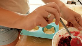 Closeup 4k video of woman making cherry fillling for pies on kitchen