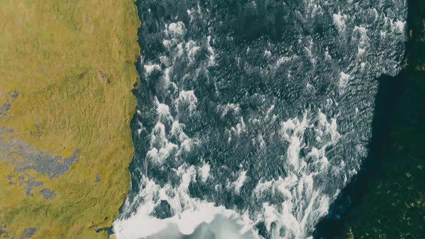 Aerial shot flying over the Skogafoss waterfall in Iceland. Rainbow sunny day.