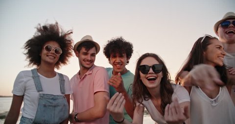 Six teen multiethnic friends having fun near lake, dancing, looking at camera, enjoying their time closeup 4k
