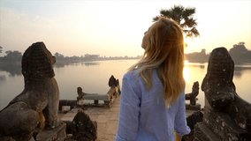 Sunrise at ancient temple, young woman tourist female contemplating the magnificent landscape from terrace over lake. People travel destinations exploration concept Asia Cambodia 