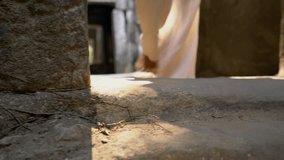 Low angle view of male's feet walking barefoot in the corridor of ancient temple from door to door - 4K video sunlight through doors 
Travel destinations hipster wander concept 
