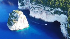 Aerial drone bird's eye view video of tropical rocky bay of Ortholithos with famous cave of Papanikolis and turquoise calm waters forming a blue lagoon, Paxos island, Ionian, Greece