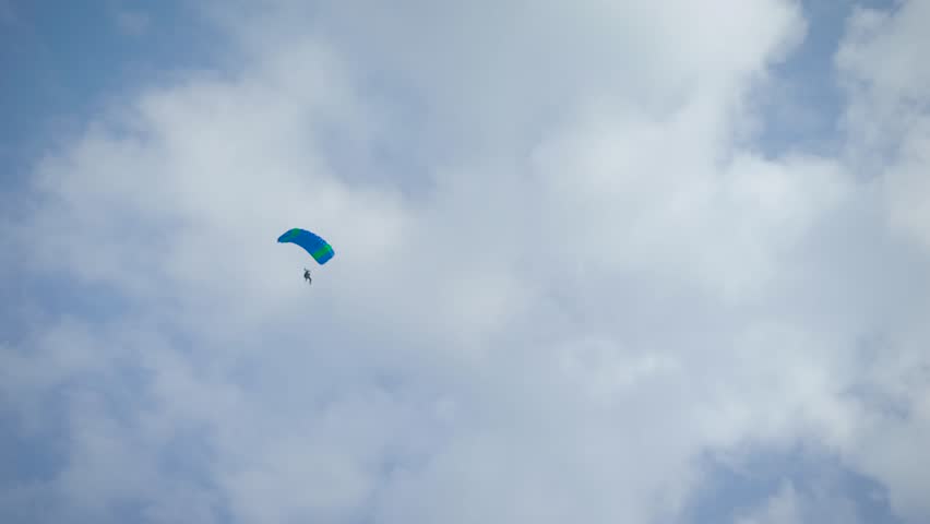 Shot from the land of a skydiver glinding in the skies, summertime.