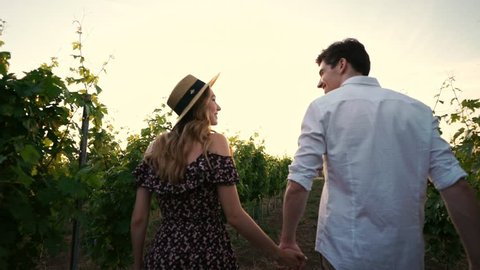 Young happy loving couple walking outdoors in the vineyard talking with each other
