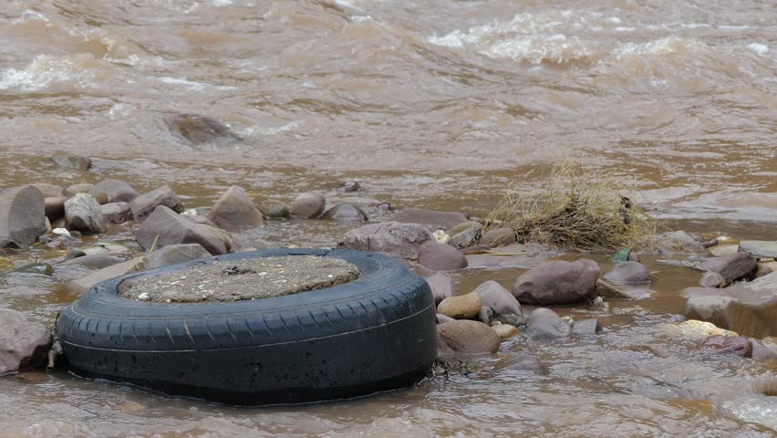 Old tire with water flow in river, rainy season, natural disaster, after flood 