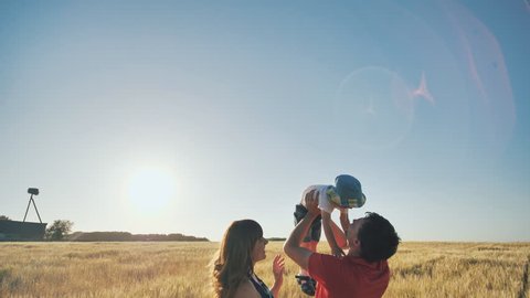 Happy parents throw up their baby, little son. Evening sunset time. Video Stok