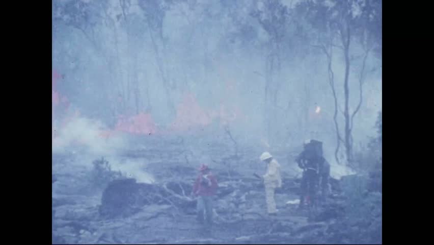 CIRCA 1973 - Tourists stand dangerously close to the lip of the Pauahi Crater, photographing splashes of lava.