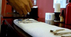 Closed-up of mixed race barber arranging barbering tools on towel at barber shop 