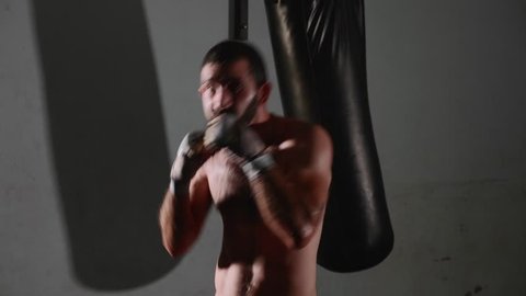 Male bearded boxer exercising shadow boxing. Fighter training punching in the darknes in slow motion.