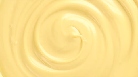 White molten chocolate swirl rotated background. Melted Milk Chocolate abstract curves backdrop. Creamy texture sweet rotation background close-up. Confectionery. UHD video Slow motion 120 fps