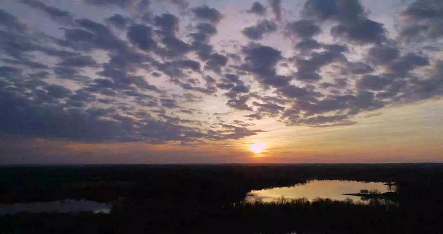 A vibrant sunset over a lake in northern Minnesota, with clouds moving towards the camera