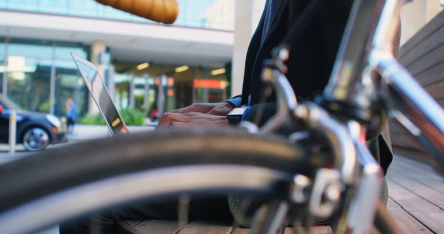 Mid section of Mixed-race businessman using laptop on street 