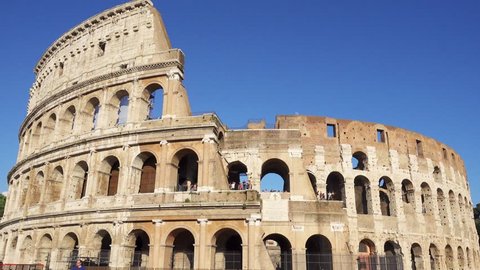 ROME, ITALY - CIRCA May 2018: Famous Italian attraction Colosseum in Rome. Veiw on ancient Flavius amphitheater Coliseum in capital of Italy. Tourists walking around. Camera moving from left to right