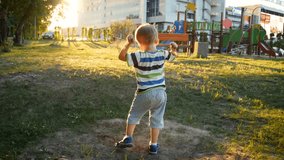 4k video of little toddelr boy playing on playground at park and throwing sand