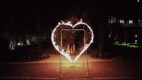 A happy couple dances and kisses through the line of fire. Fire heart on fire show