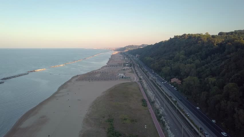 
aerial view of mountain with national road, railway line and moving train, cycle path, beach and sea near Pesaro Town in Italy