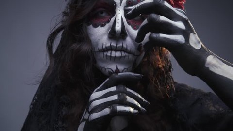 Make-up for Halloween, sugar Mexican skull, make-up. The girl beckons to herself. Slow motion