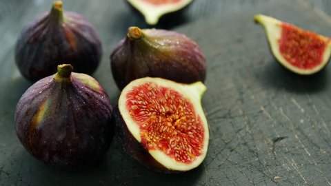Arrangement of whole and cut fresh ripe figs with soft juicy flesh composed on rough wooden table