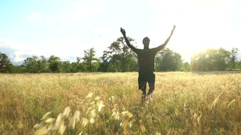 Young man wearing black stocking on head, arms and legs runs in the middle of flower field, happy, inspired, motivated, winner